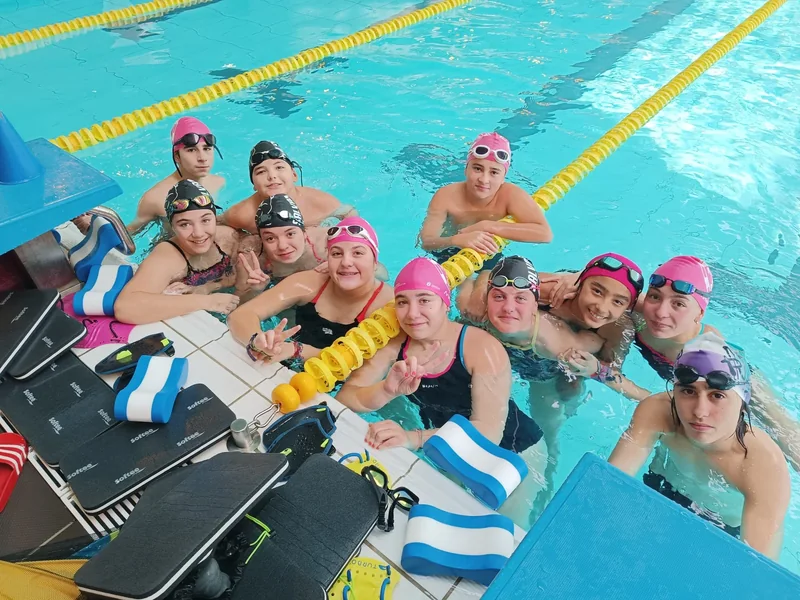 Grupo de deportistas na piscina con gorros e material de adestramento